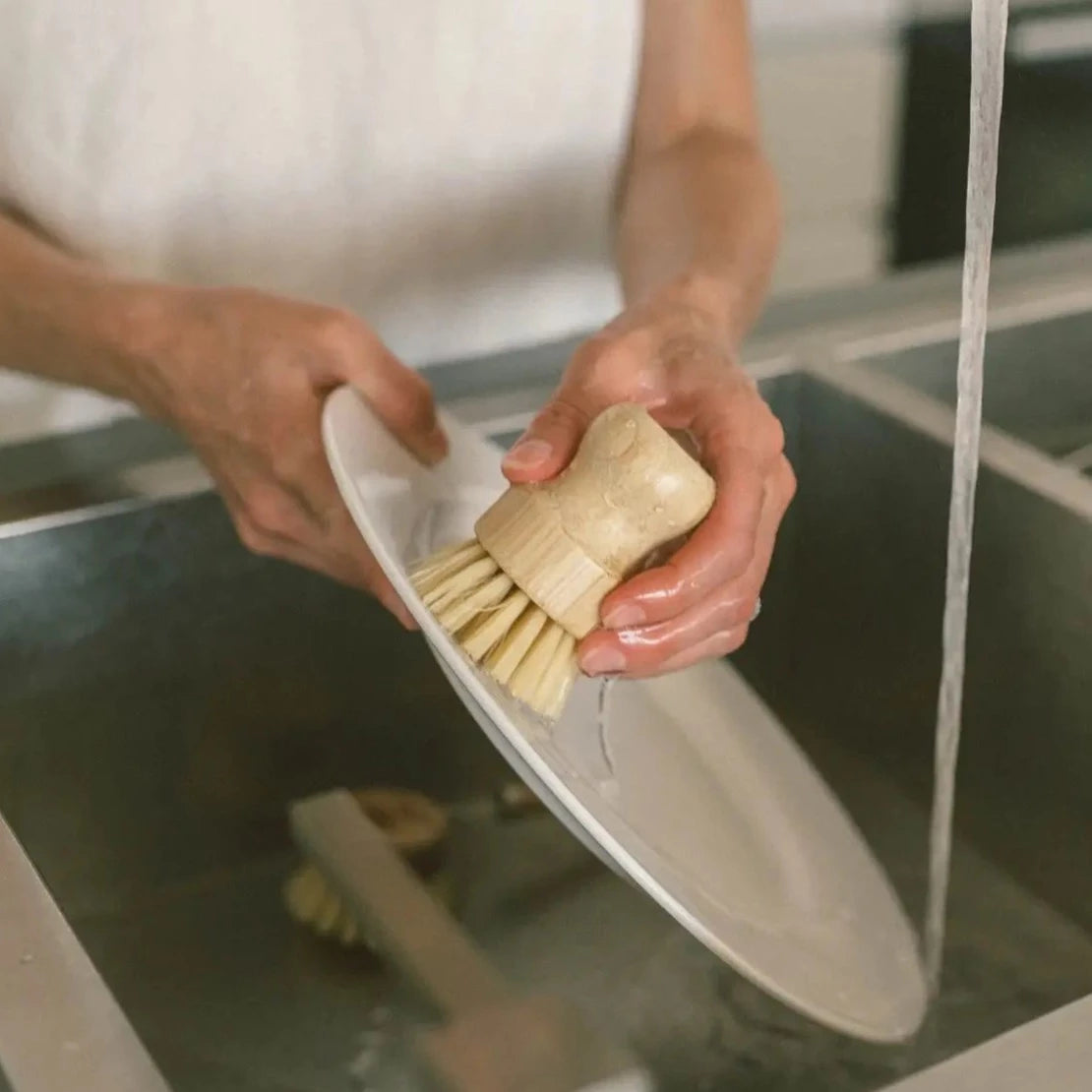Woman washing a dish with Woman holding ergonomic Sisal Brush