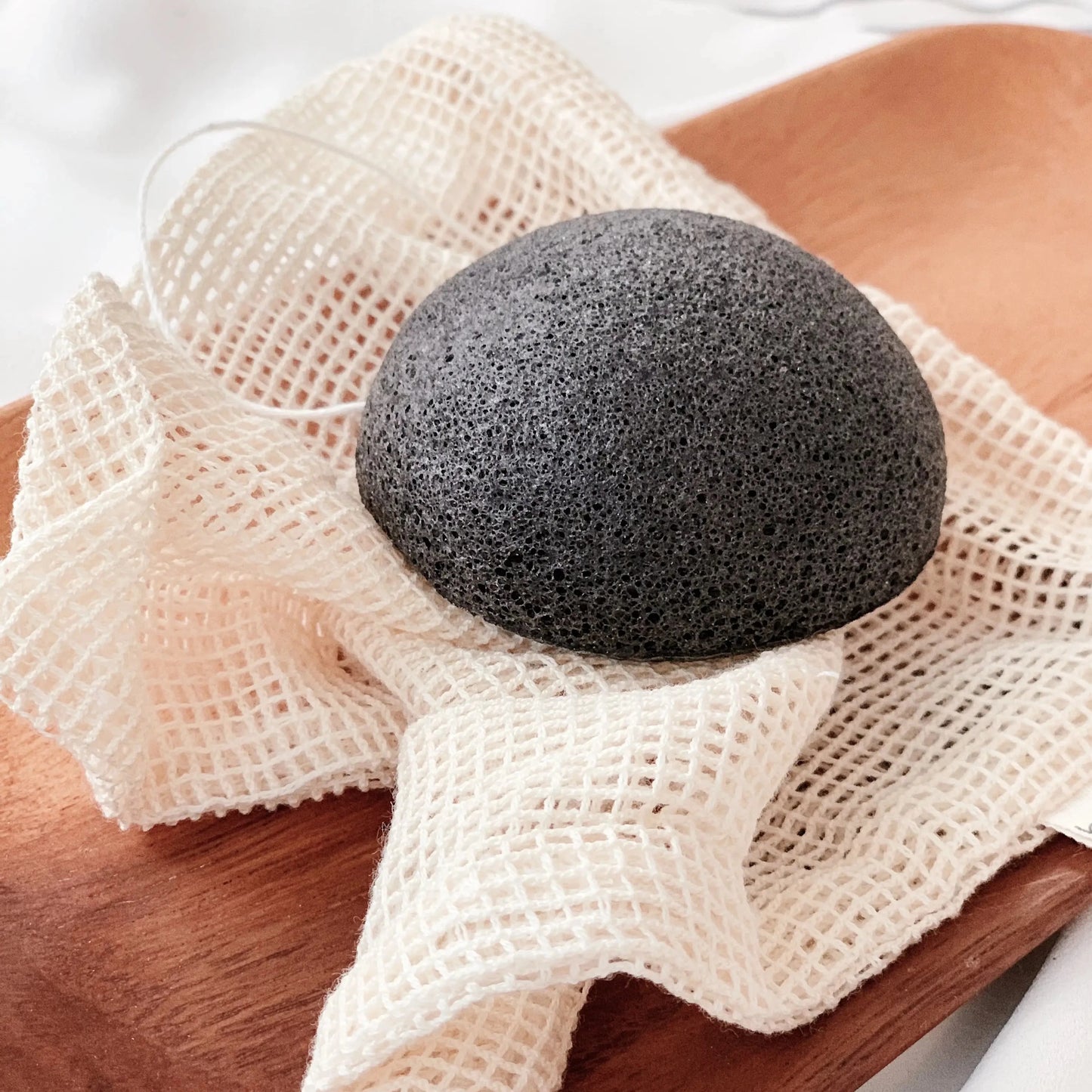 black konjac sponge with hanging string. exfoliate gently. conjac plant and carbon. side view
