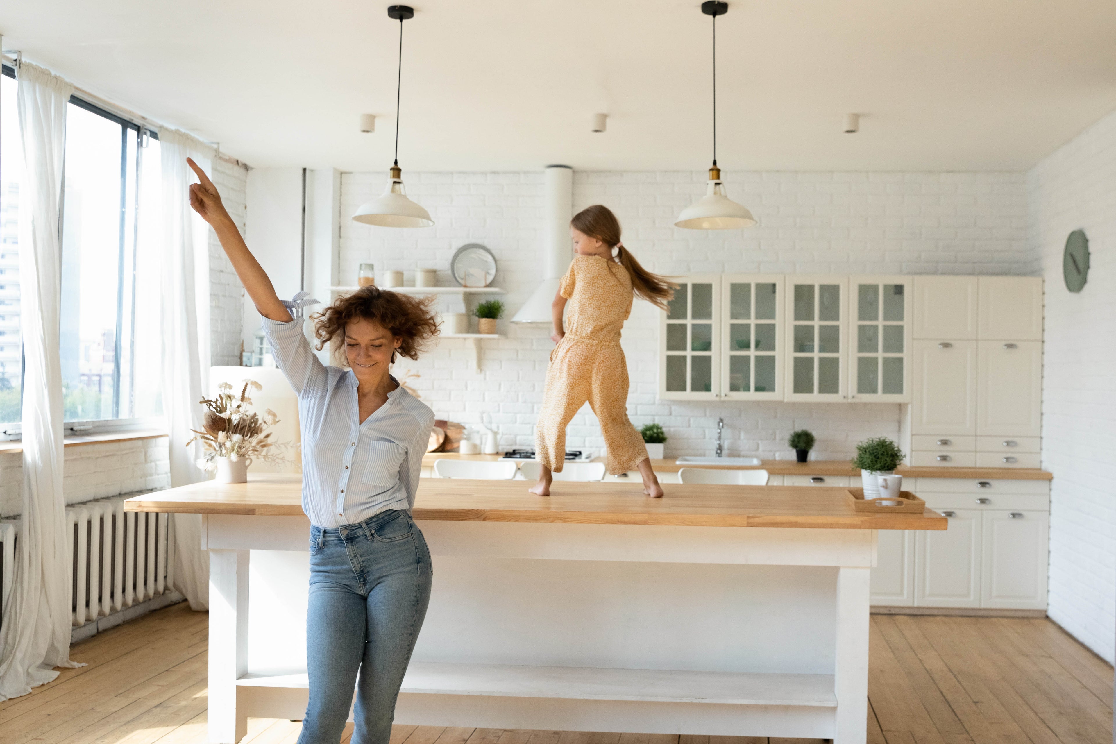 mother daughter dancing in clean kitchen