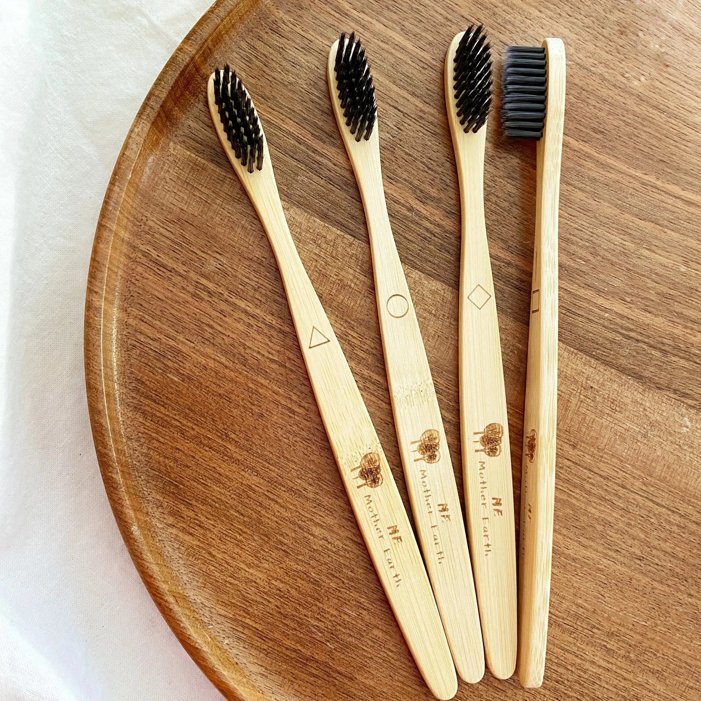 bamboo tooth brushes with active carbon bristles extra soft.  geometric shapes to tell them apart.  Displayed on walnut wood tray