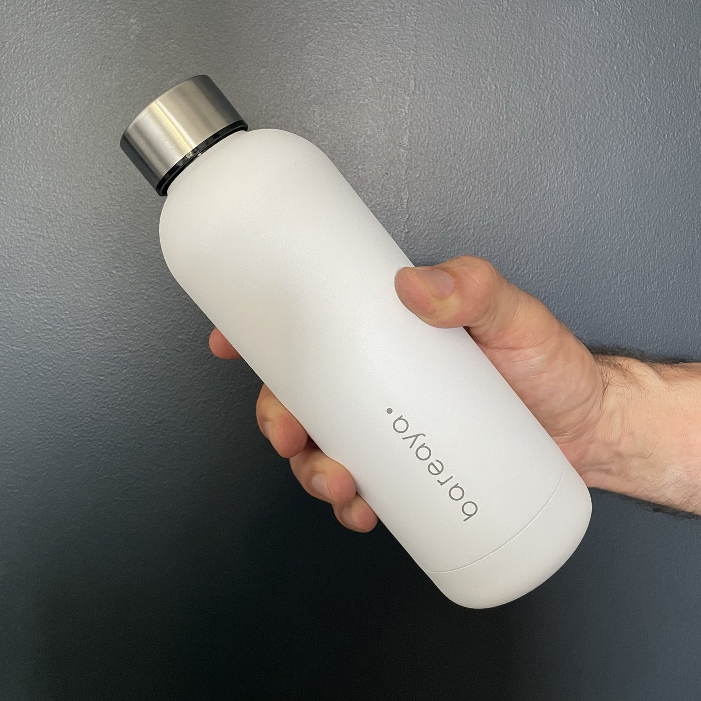 man holding white water bottle against a black background