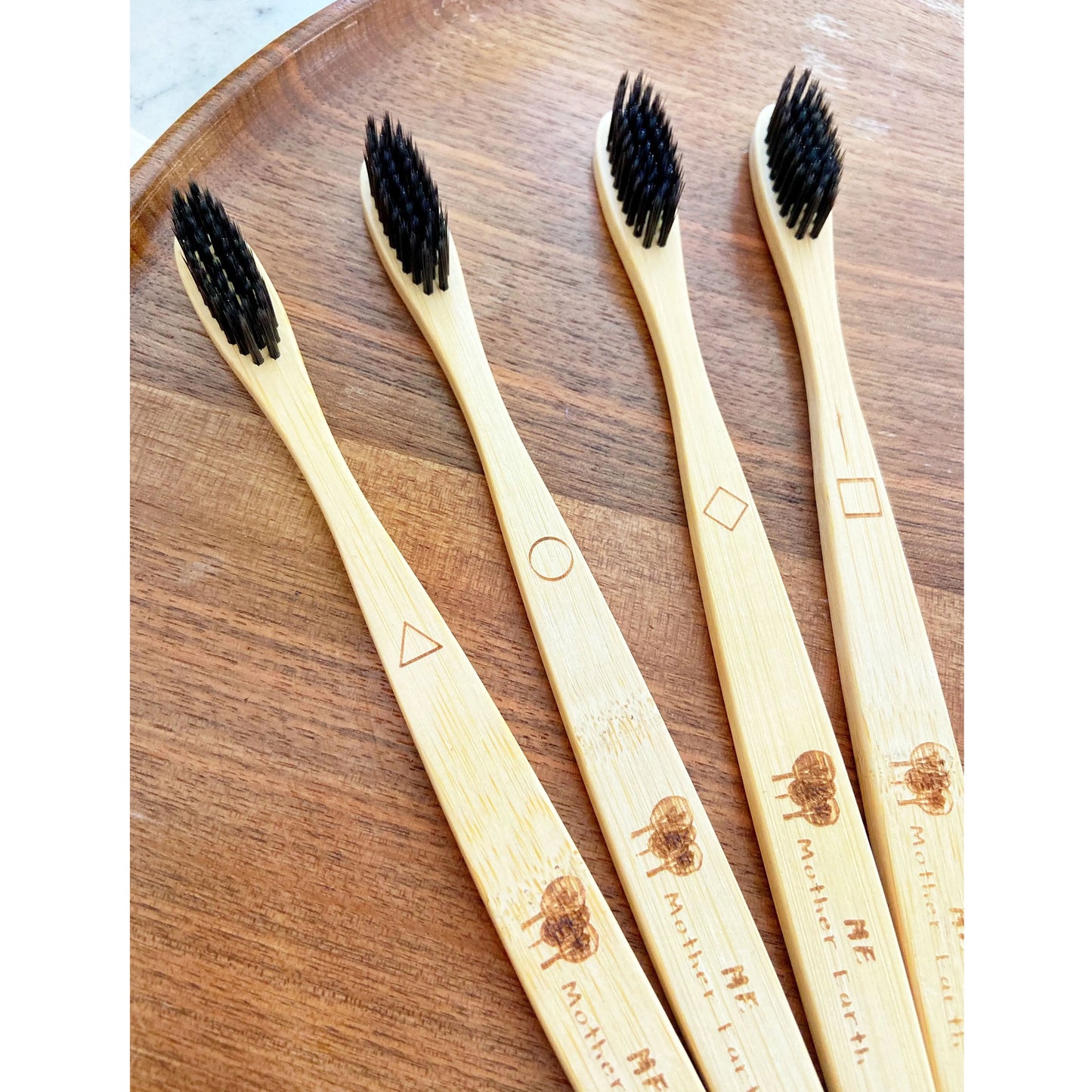 Bamboo Charcoal toothbrush - geometric markings for distinguishing users - sustainable - Bamboo toothbrush on walnut tray