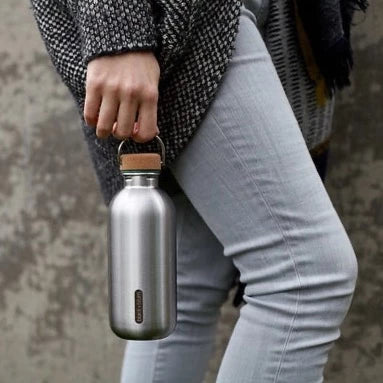 Woman carrying stainless steel water bottle with cork lid