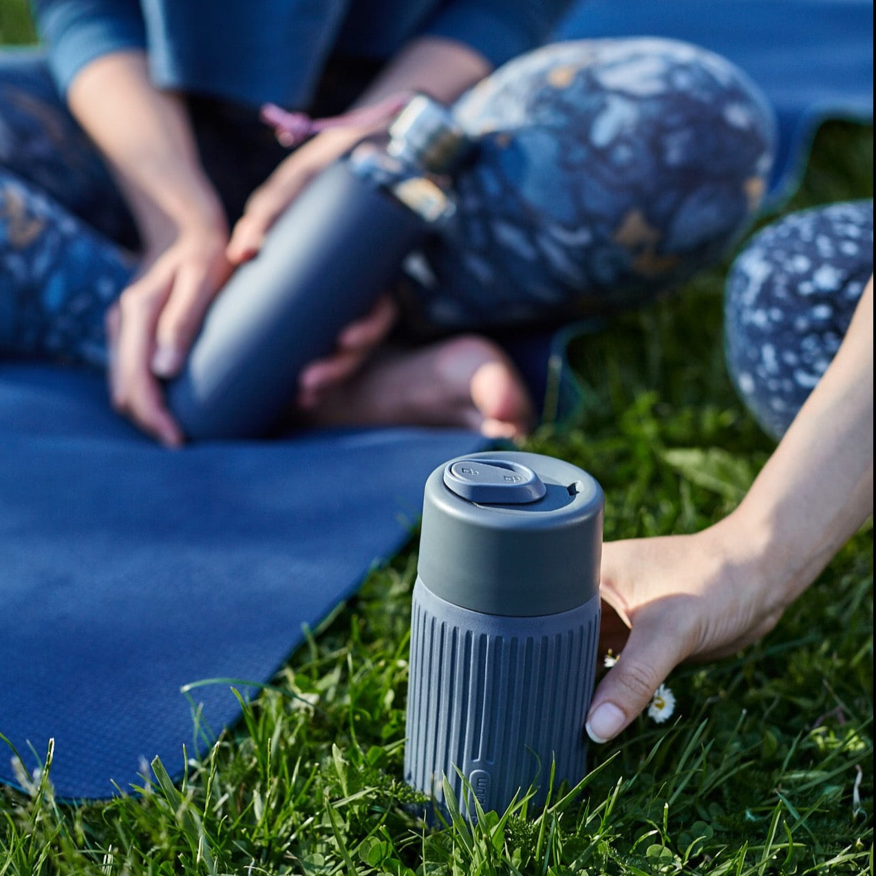 Slate colored glass travel cup being used during a picnic on the grass