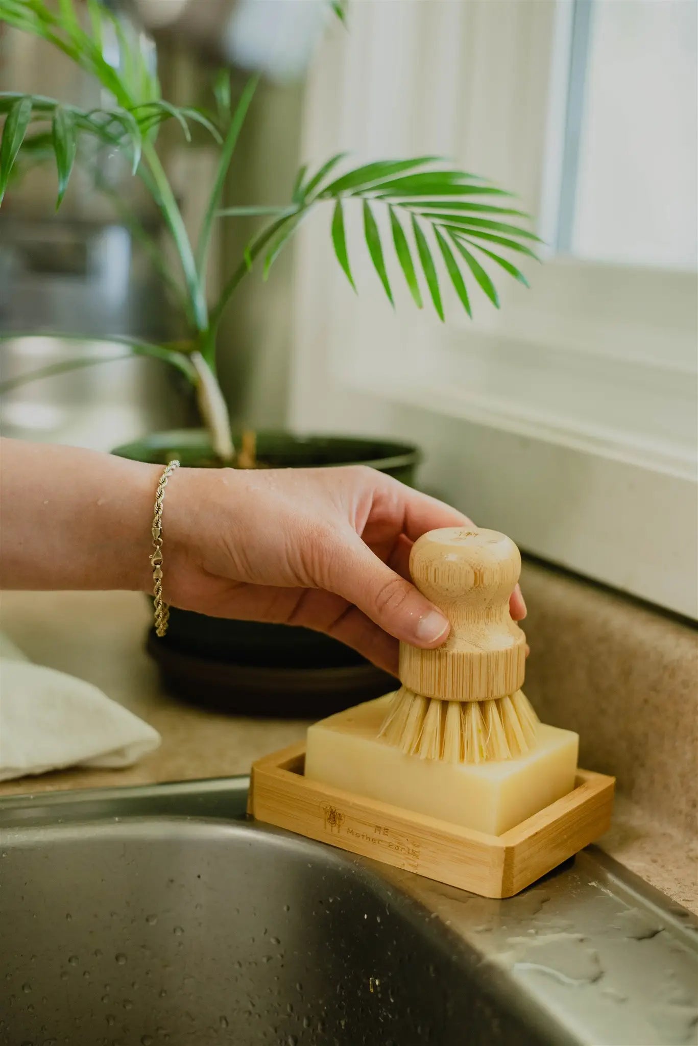 Bamboo soap dish in use with dishwashing soap bar and woman holding a cleaning brush