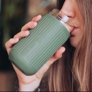 Woman sipping drink from glass travel cup